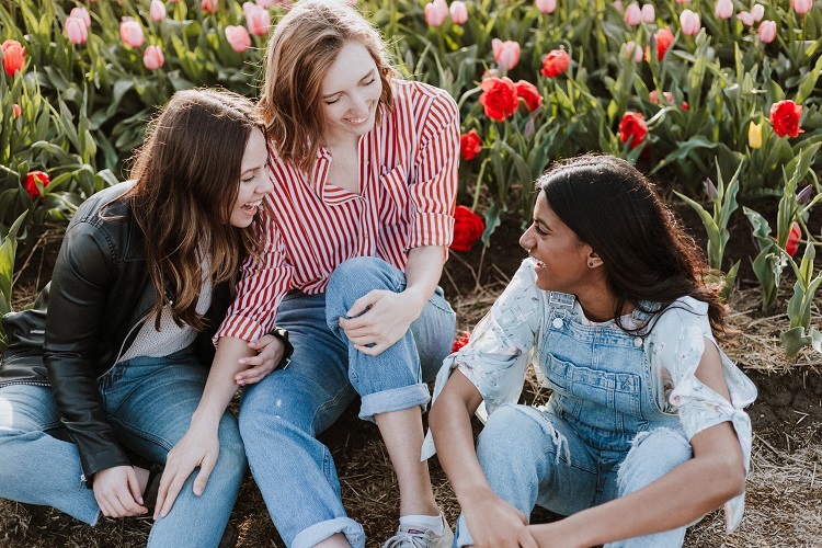 A group of Autistic women is sitting next to a tulip fields, laughing.